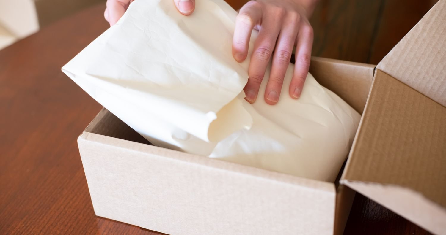 Hands packing a product into a branded box by hand