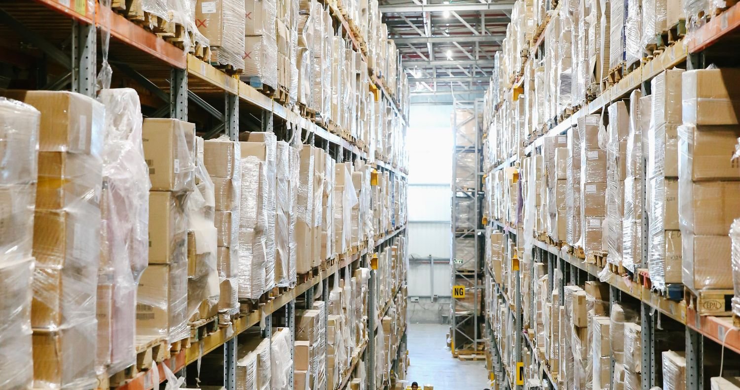 Pallet racking aisle stacked with wrapped inventory in a warehouse